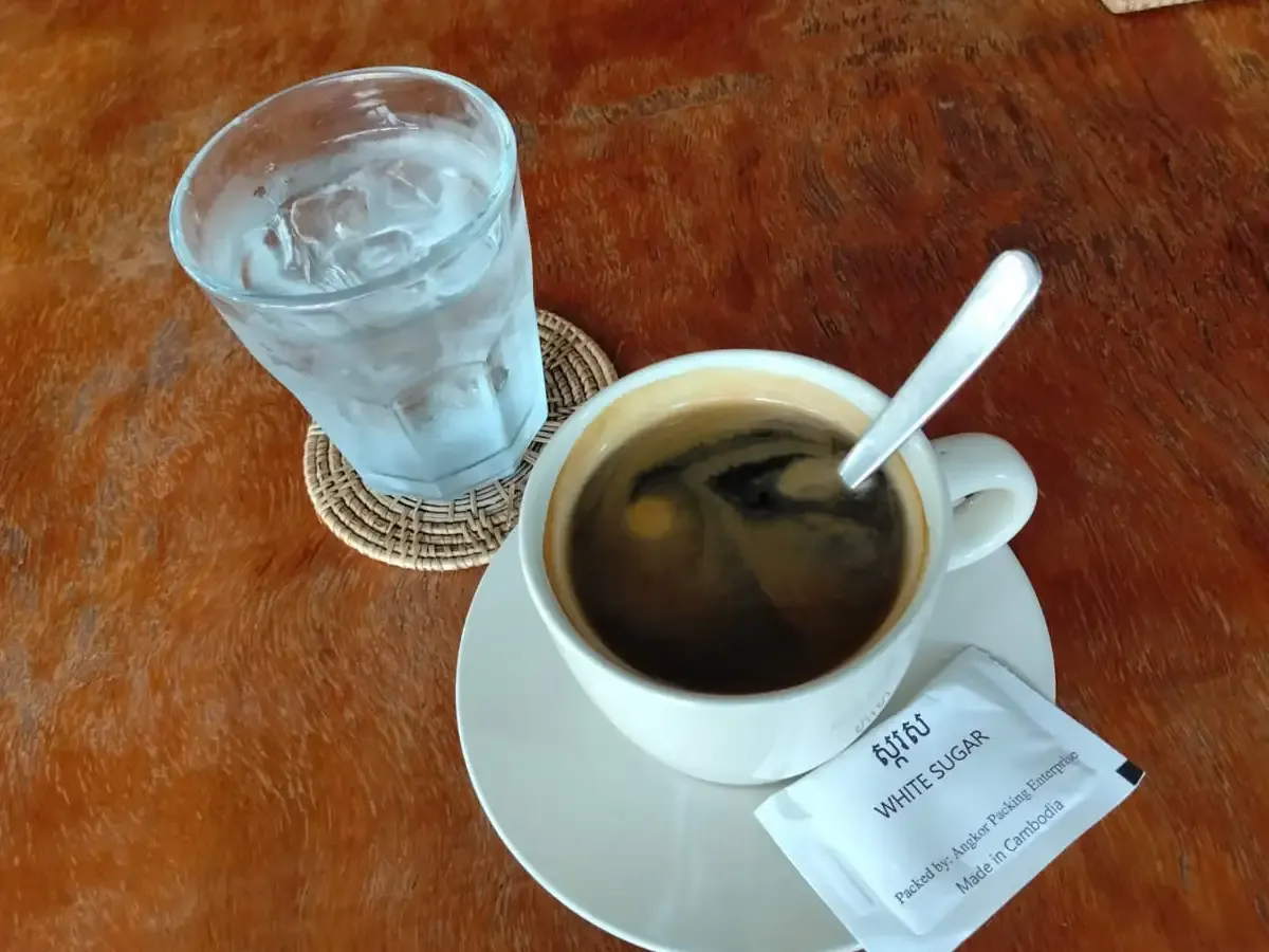Americano with a glass of iced water and a sugar sachet at Amun Bar & Restaurant