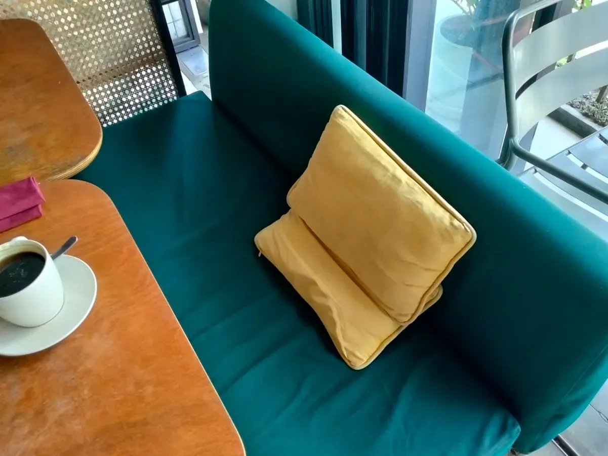 Green upholstered bench with a yellow cushion at Amun Bar & Restaurant