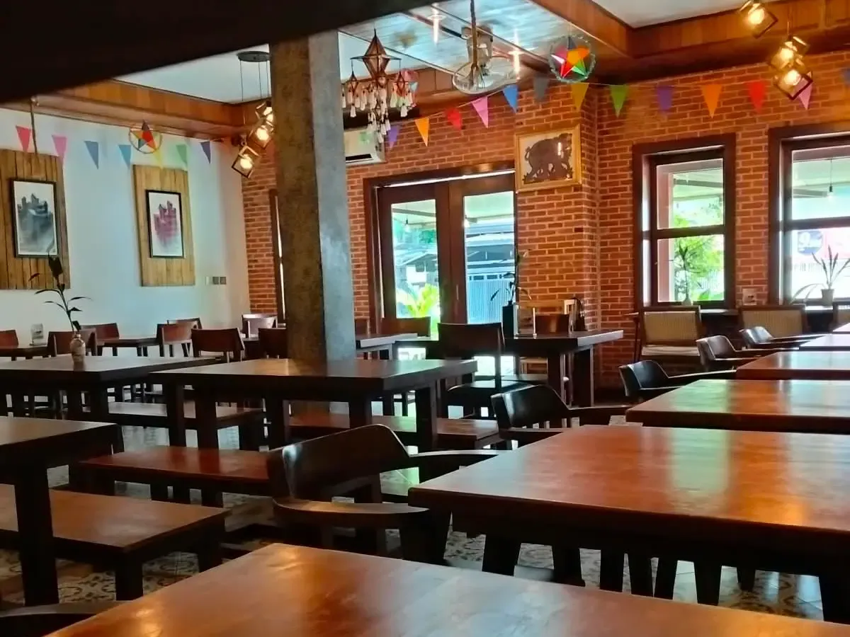Dining room of The Source Café, with brick walls, wooden tables and colored bunting