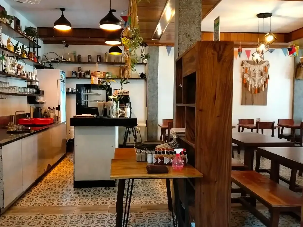 Counter and dining room of The Source Café, with patterned floor tiles and wooden tables