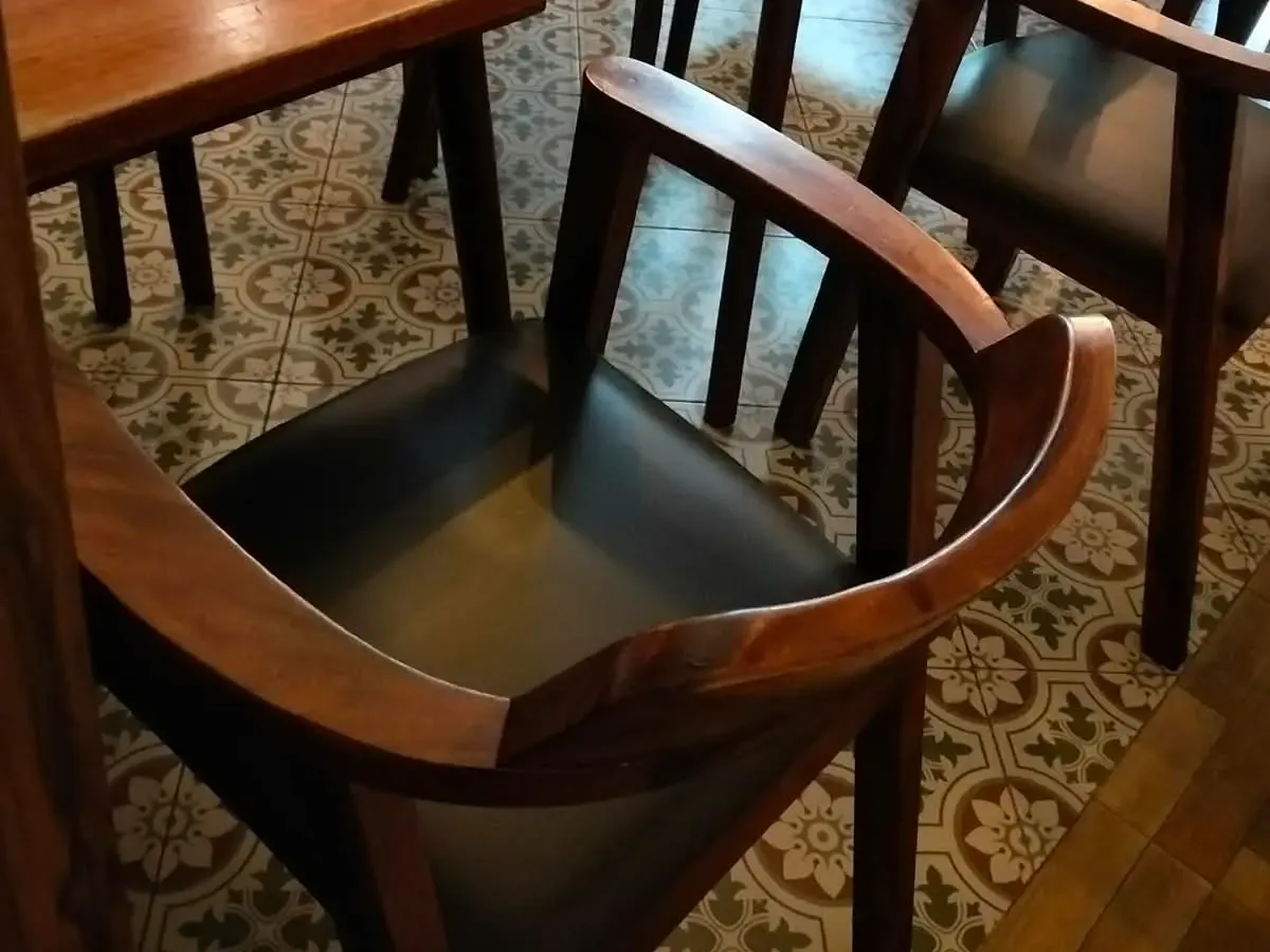 Wooden armchair with a dark leather seat at The Source Café
